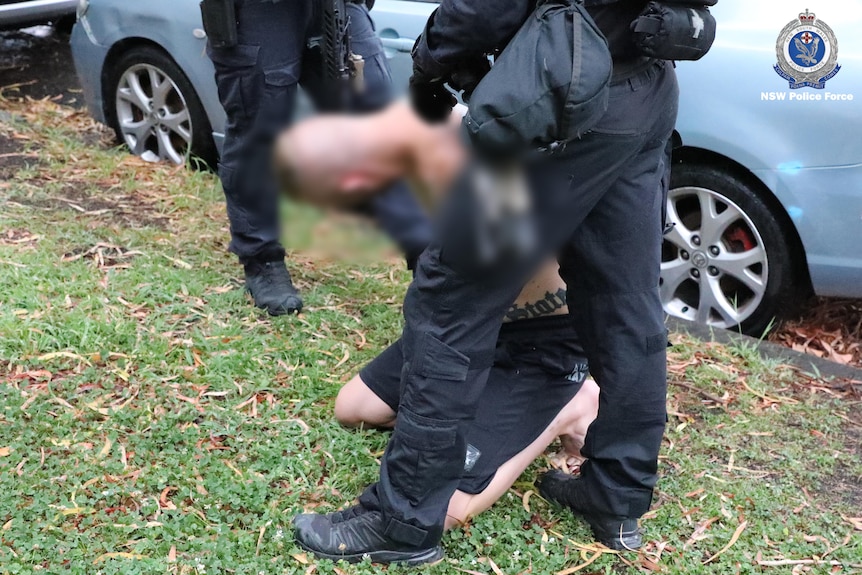 A man on his knees is arrested by police
