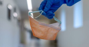 A nurse holds a surgical mask.