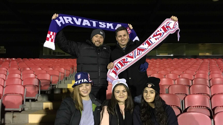 Croatian-Australian football fans in the stands at a Melbourne stadium hold scarfs.