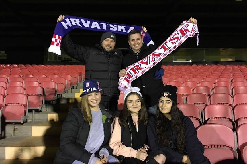 Croatian-Australian football fans in the stands at a Melbourne stadium hold scarfs.