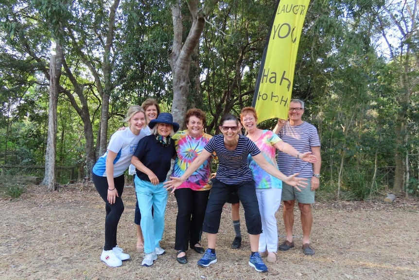 A group of people smiling beside a 'Laughter Yoga' banner