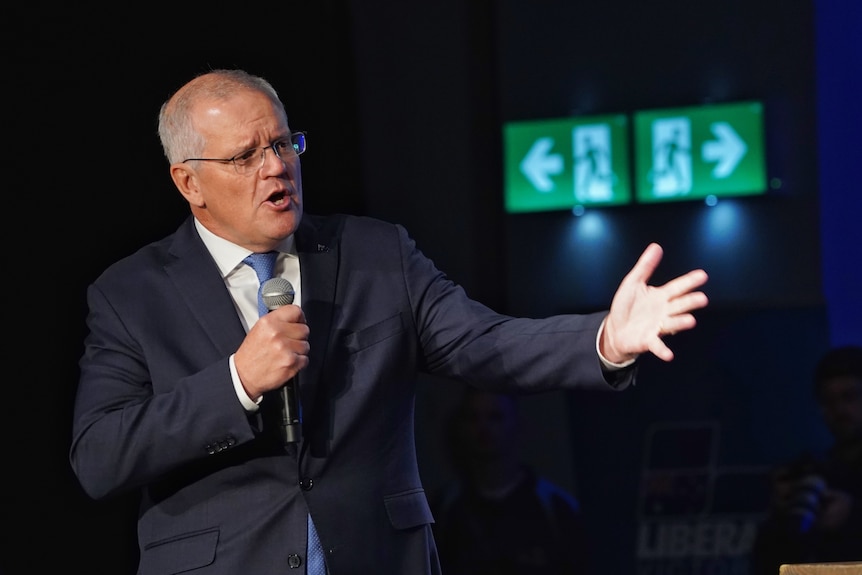 Scott Morrison speaks into a microphone with an arm outreached. 