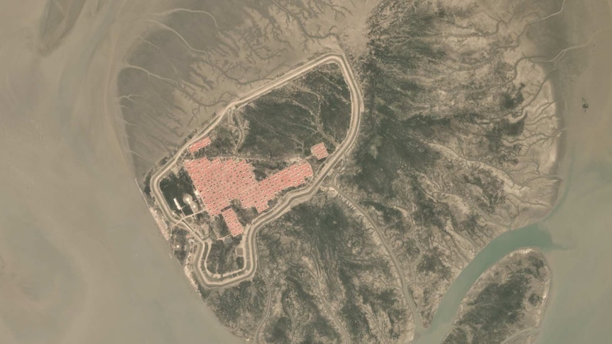 A satellite image showing roads and red roofs of houses appearing on a small island