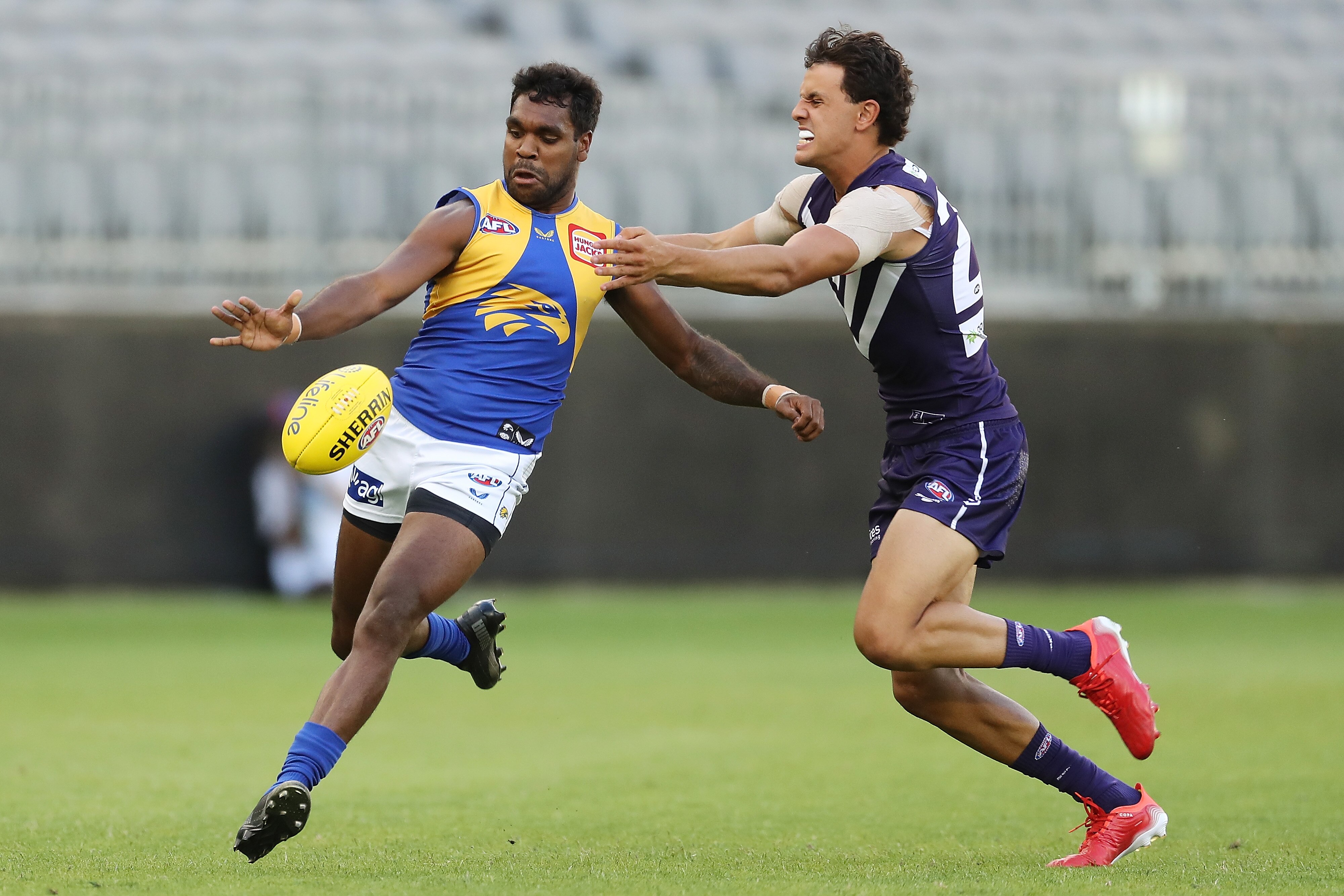 Liam Ryan drops the ball to kick it as Heath Chapman approaches