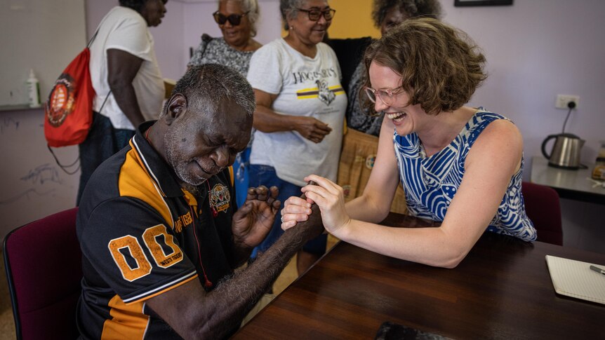 an aboriginal man squeezing the hand of a young woman in celebration