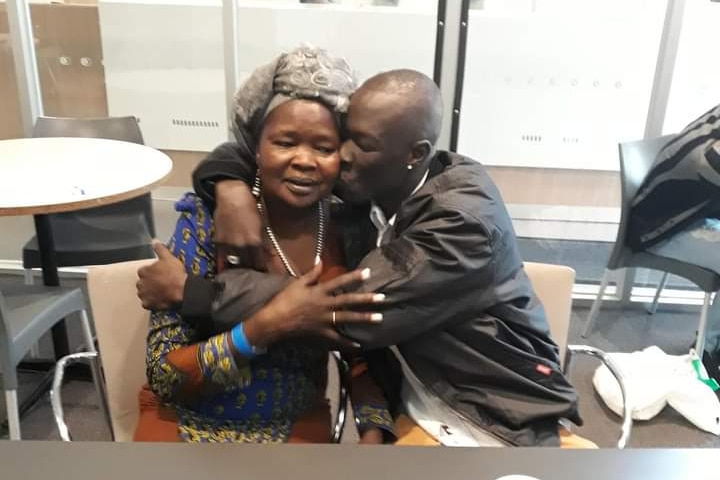 Juma Chol kisses his mother while they sit in a detention centre