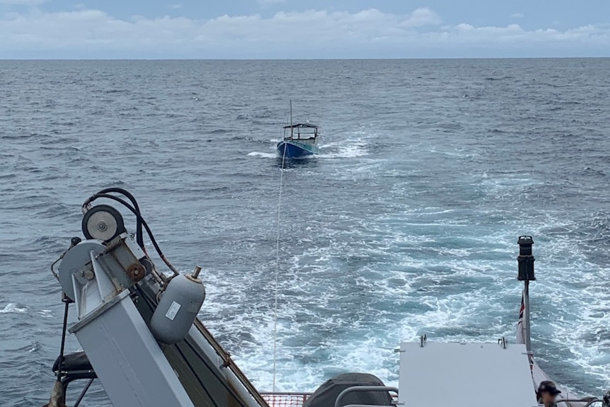 a small Indonesian vessel being towed by a large ship.