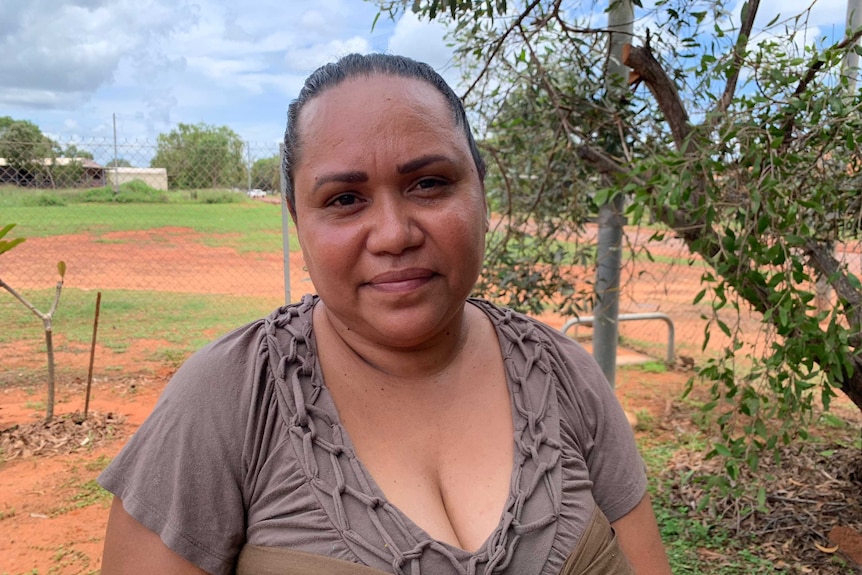 Jacquline Philips in a brown dress outside with green fields and red dirt behind her.