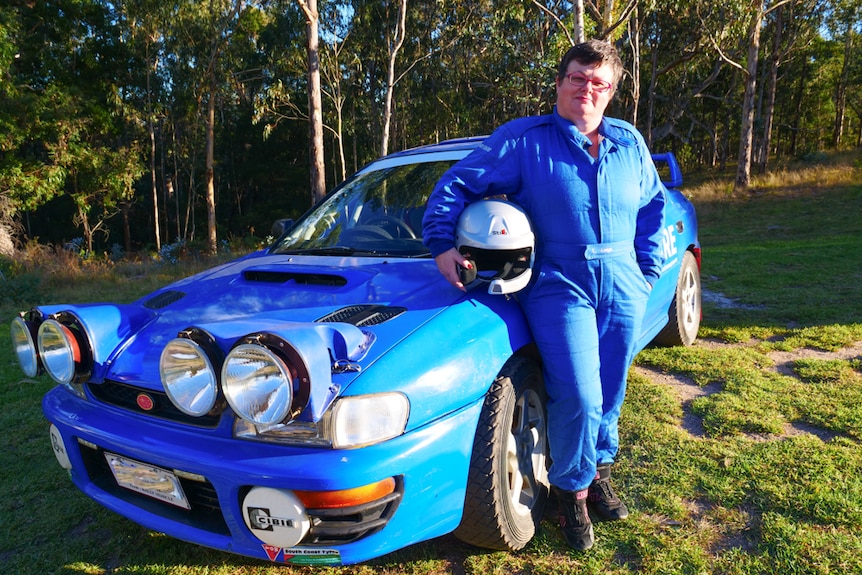 Portrait of female rally driver beside her car