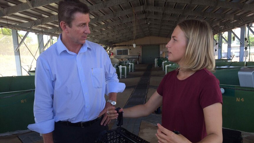 NT Fisheries Minister Willem Westra van Holthe speaks with research officer Samantha Nowland who holds an oyster grow out cage