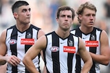 Collingwood players have their hands on their hips and look frustrated while walking off the MCG