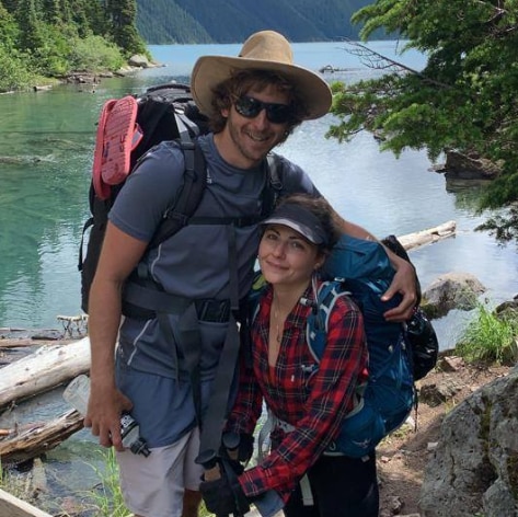 A couple smile at the camera in the mountains