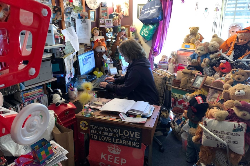Caryn Hearsch sits on a computer in a room full of toys.