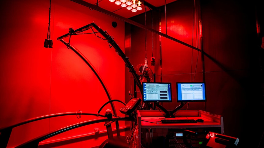 A treadmill is connected to several computers and surrounded by fans and heat lamps.