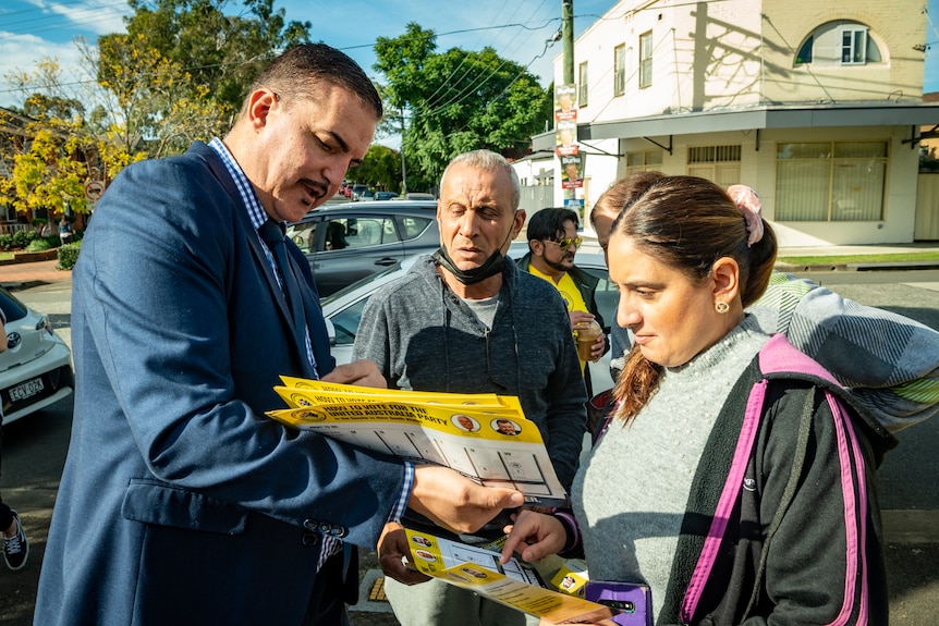 John Koukoulis showing some UAP pamphlets to a man and a woman in western Sydney.