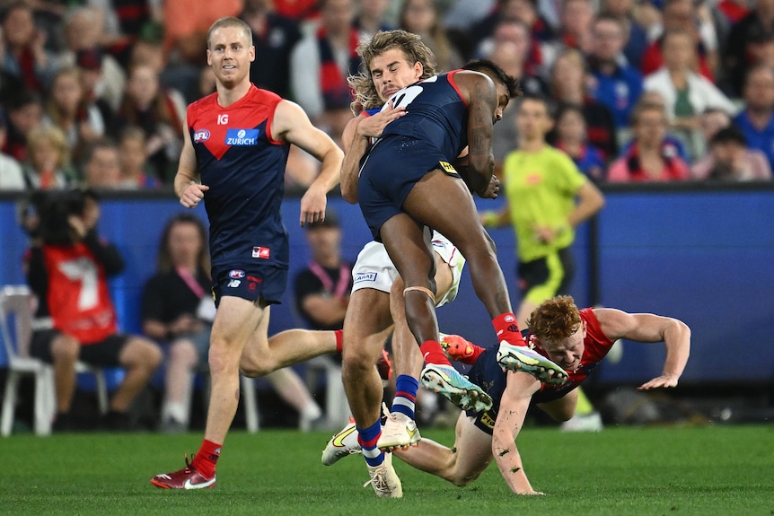 Kysaiah Pickett jumps as he hits Bailey Smith with a bump during an AFL game between Melbourne Demons and Western Bulldogs.