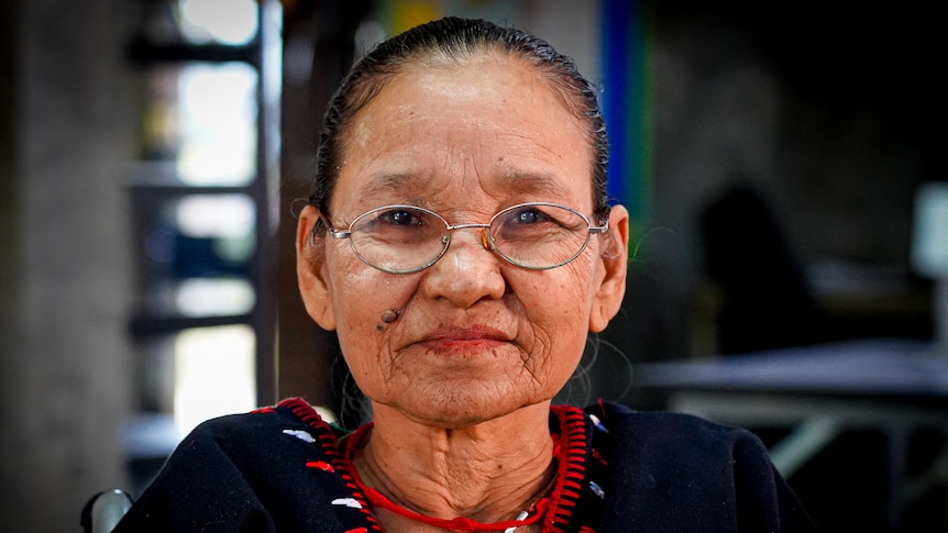 An older Burmese woman in glasses sits in a wheelchair