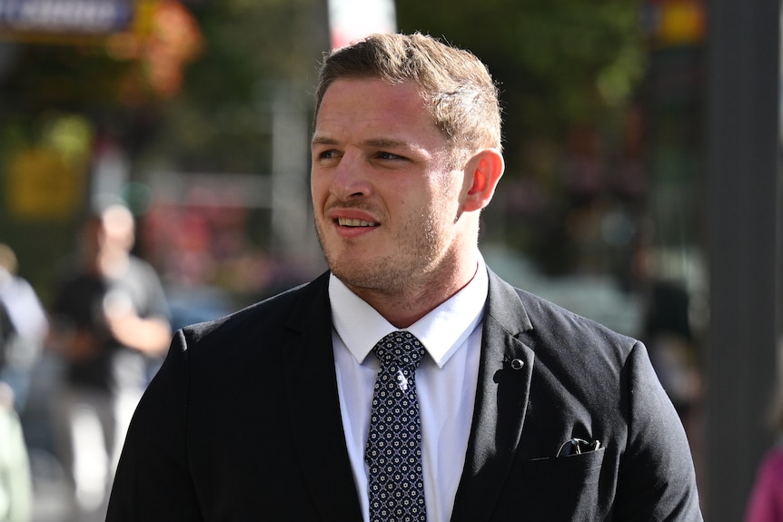 Caucasian man in a suit and tie, outside walking towards court
