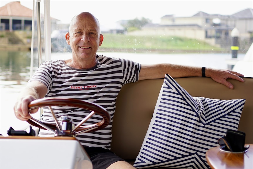 John McColl sits at boat steering wheel