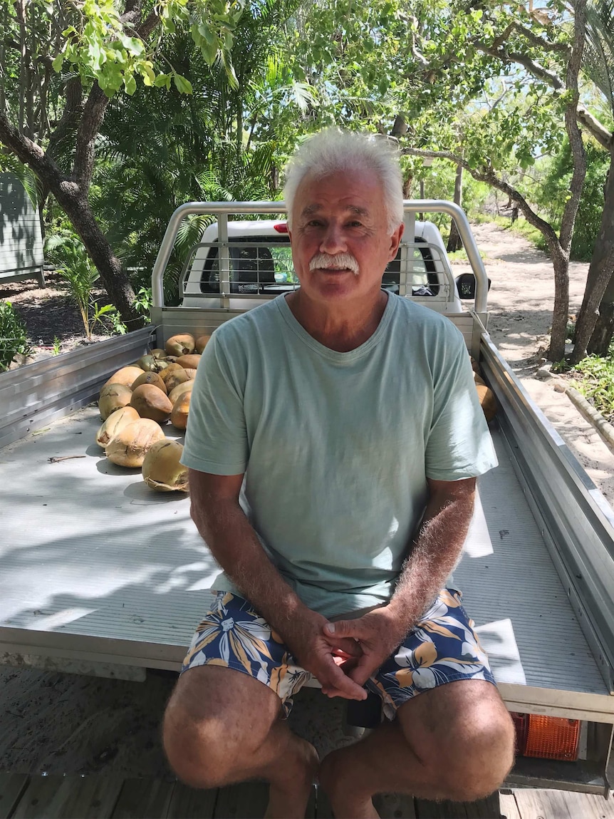 A man sitting in a ute with trees in background