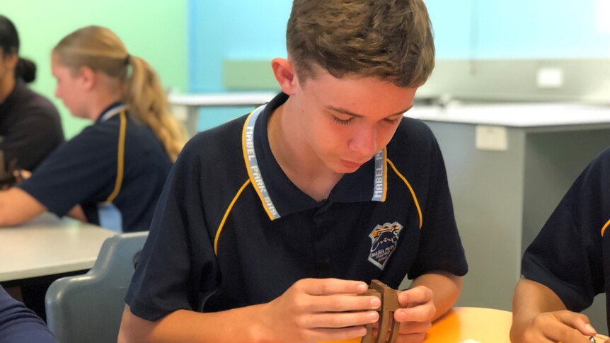 Year 8 student Dean Kilpatrick works at a desk in a classroom.