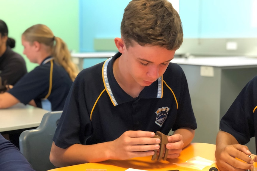 Year 8 student Dean Kilpatrick works at a desk in a classroom.