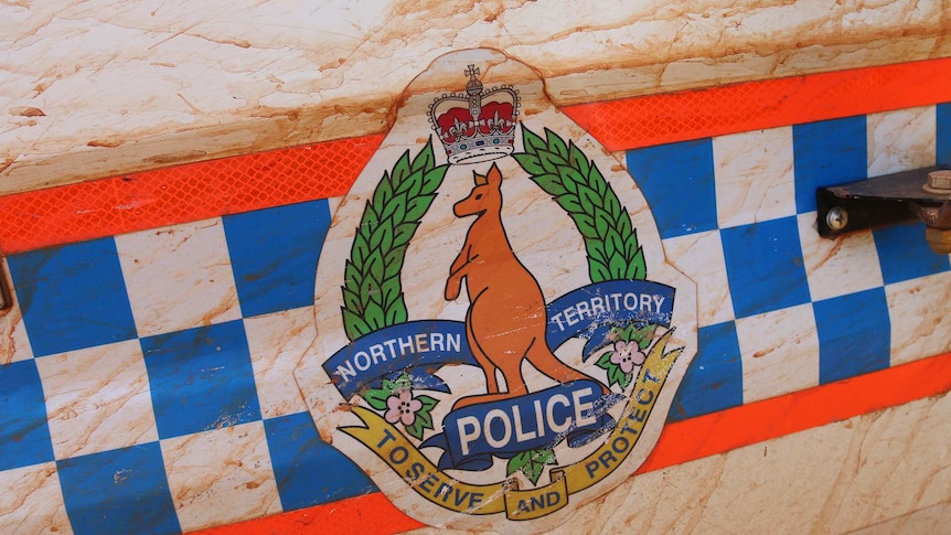 NT Police insignia on mud-splattered car door.