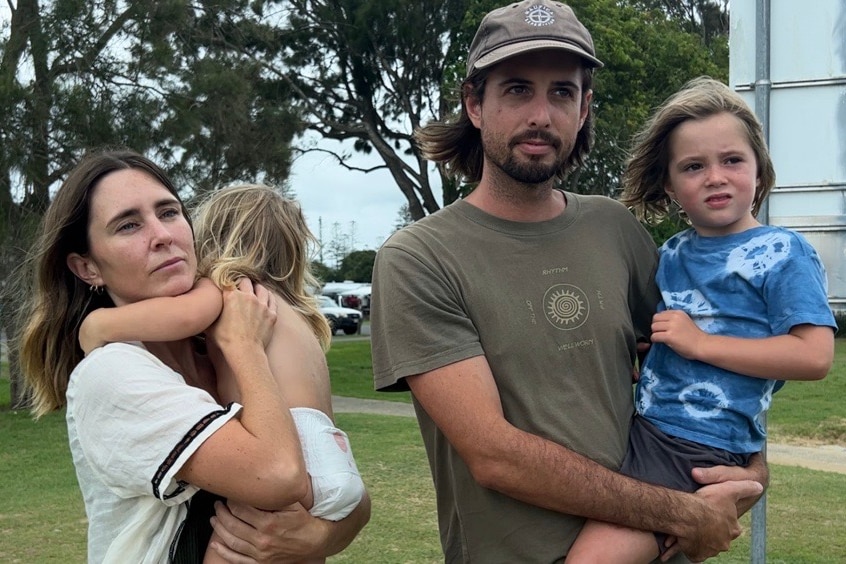 Young family in Bellingen standing carrying two young children 