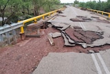 A highway which has been smashed up with water running under the bridge. 
