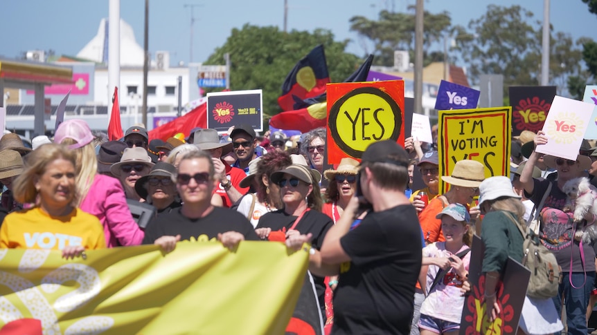 A crowd of people holding signs and banners in support of the Voice to Parliament in Tweed Heads.