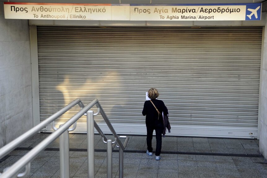 A commuter reading a notice at a central metro station during a 24-hour general strike in Athens, Greece November 12, 2015