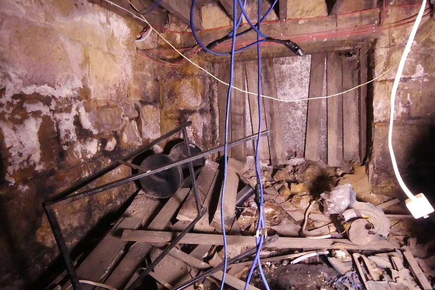 Boarded up doorway in small underground room with debris and clutter.