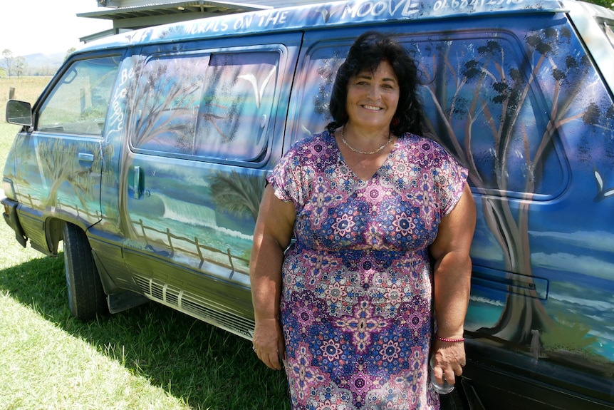 Woman in front of painted van smiling.