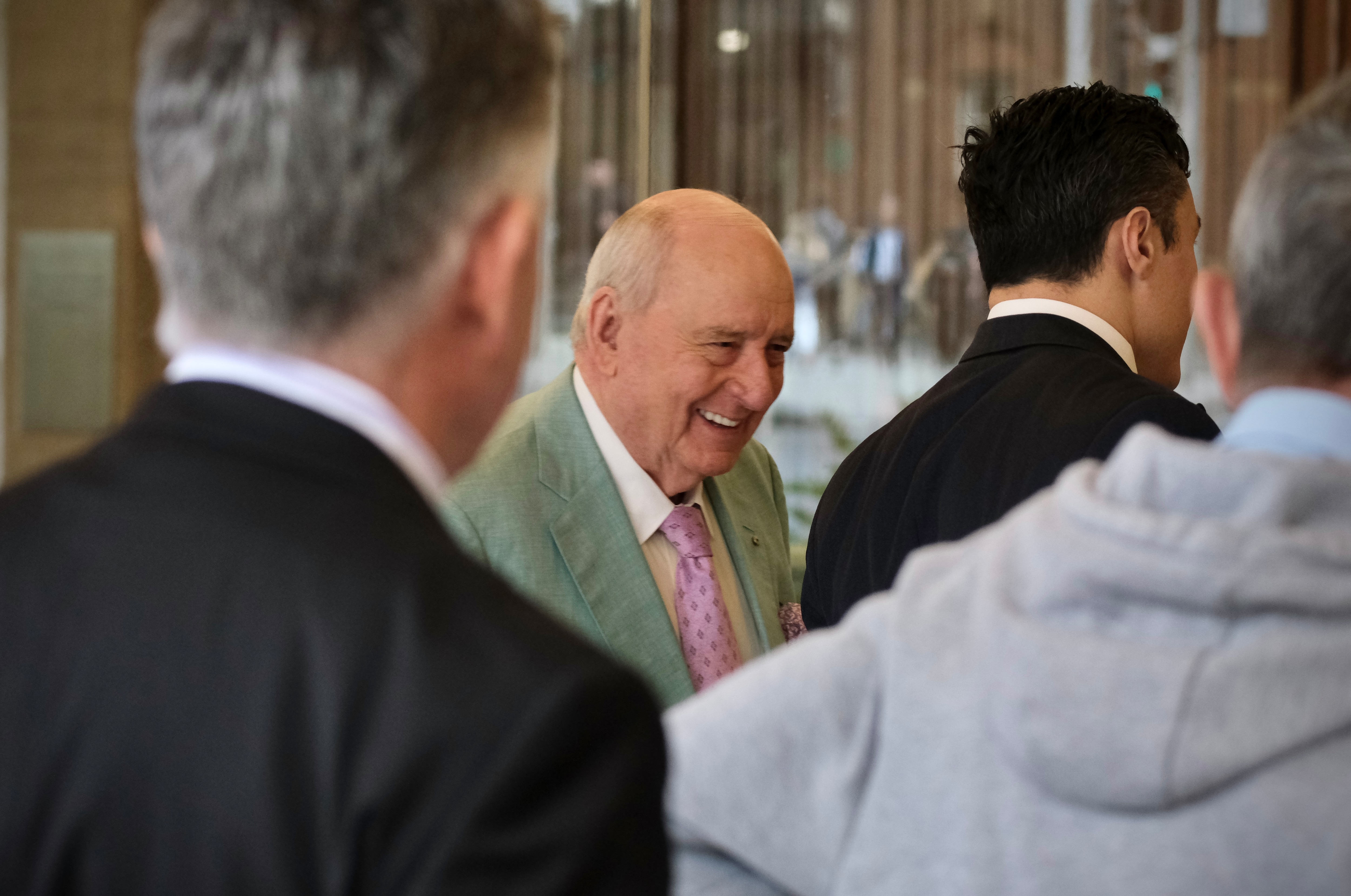 Mr Jones in a mint-coloured blazer with a pink tie smiling as he walks on a city street.