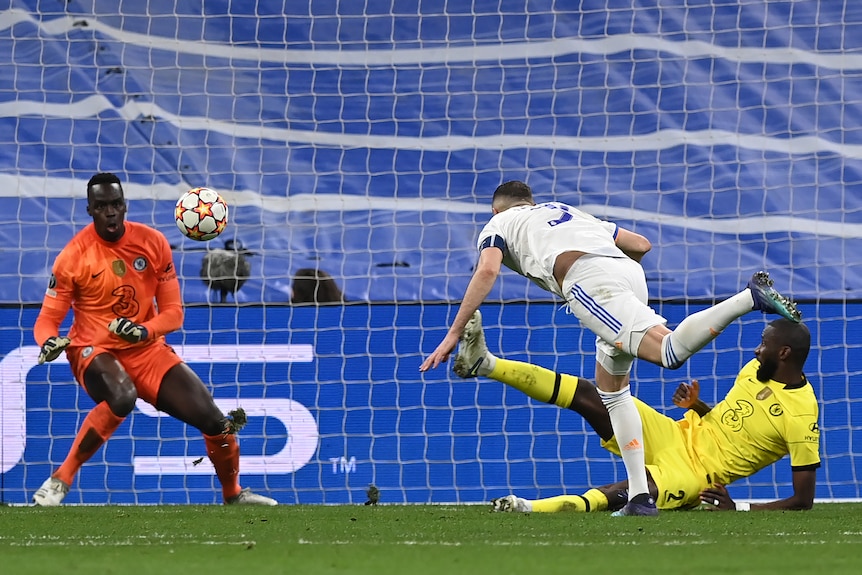 A Real Madrid striker dives forward after heading the ball past the Chelsea goalkeeper in the Champions League.