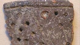 Ancient stone fragment with holes in it.