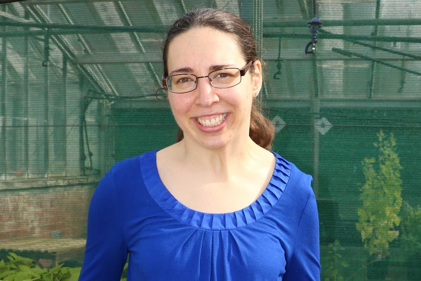 Dr Felicity Denham standing in front of some fresh green plants.