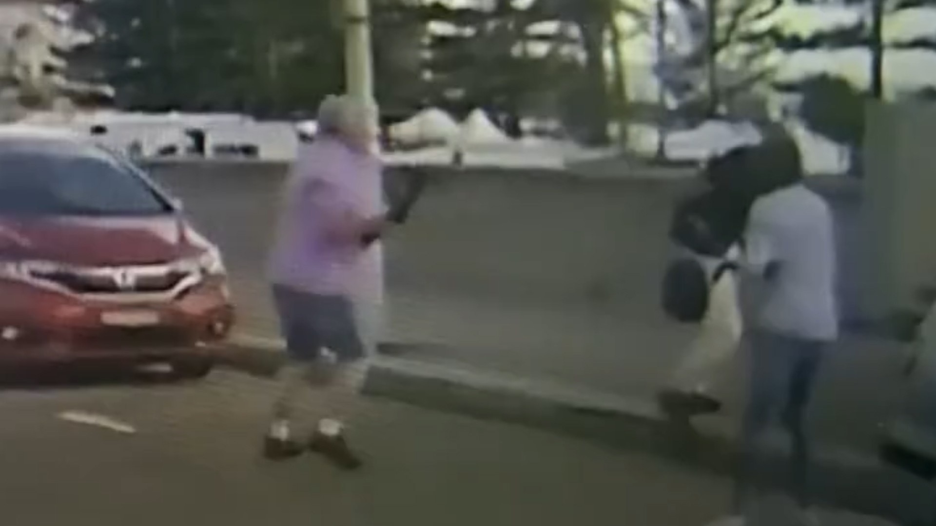 Um homem de camisa roxa segura brevemente a arma do atirador de Bondi.