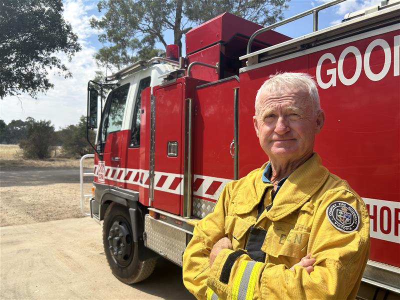 Un miembro de la CFA se encuentra frente a un camión de bomberos rojo. 