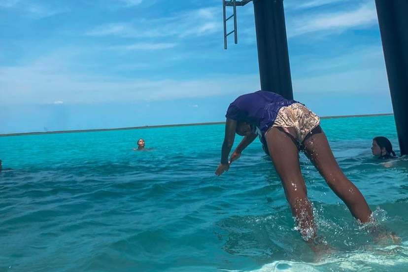 A girl dives into the water under a jetty.