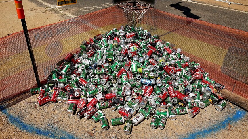 A mound of cans lie under a basketball hoop in a camping ground.