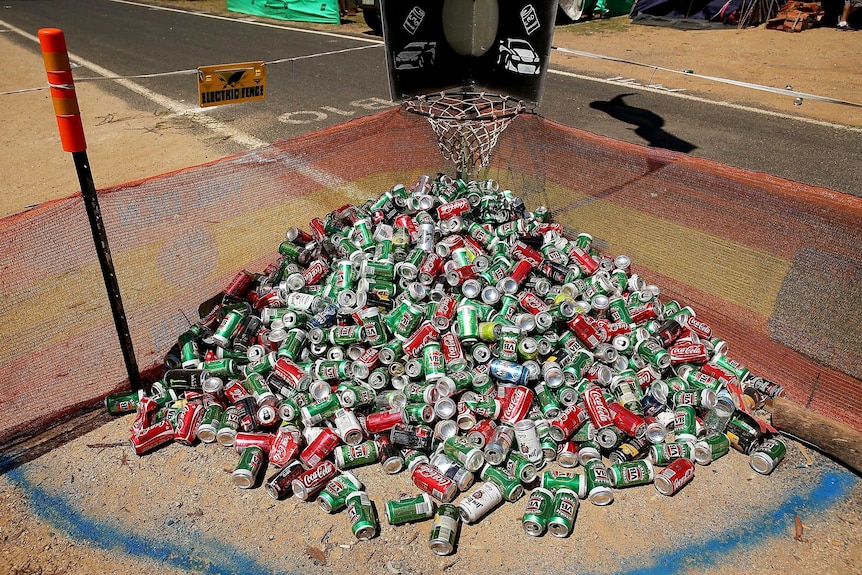 A mound of cans lie under a basketball hoop in a camping ground.