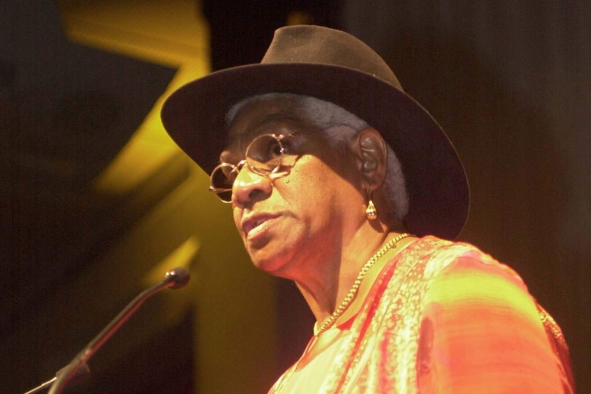 Evelyn Scott stands at a lectern speaking into a microphone.