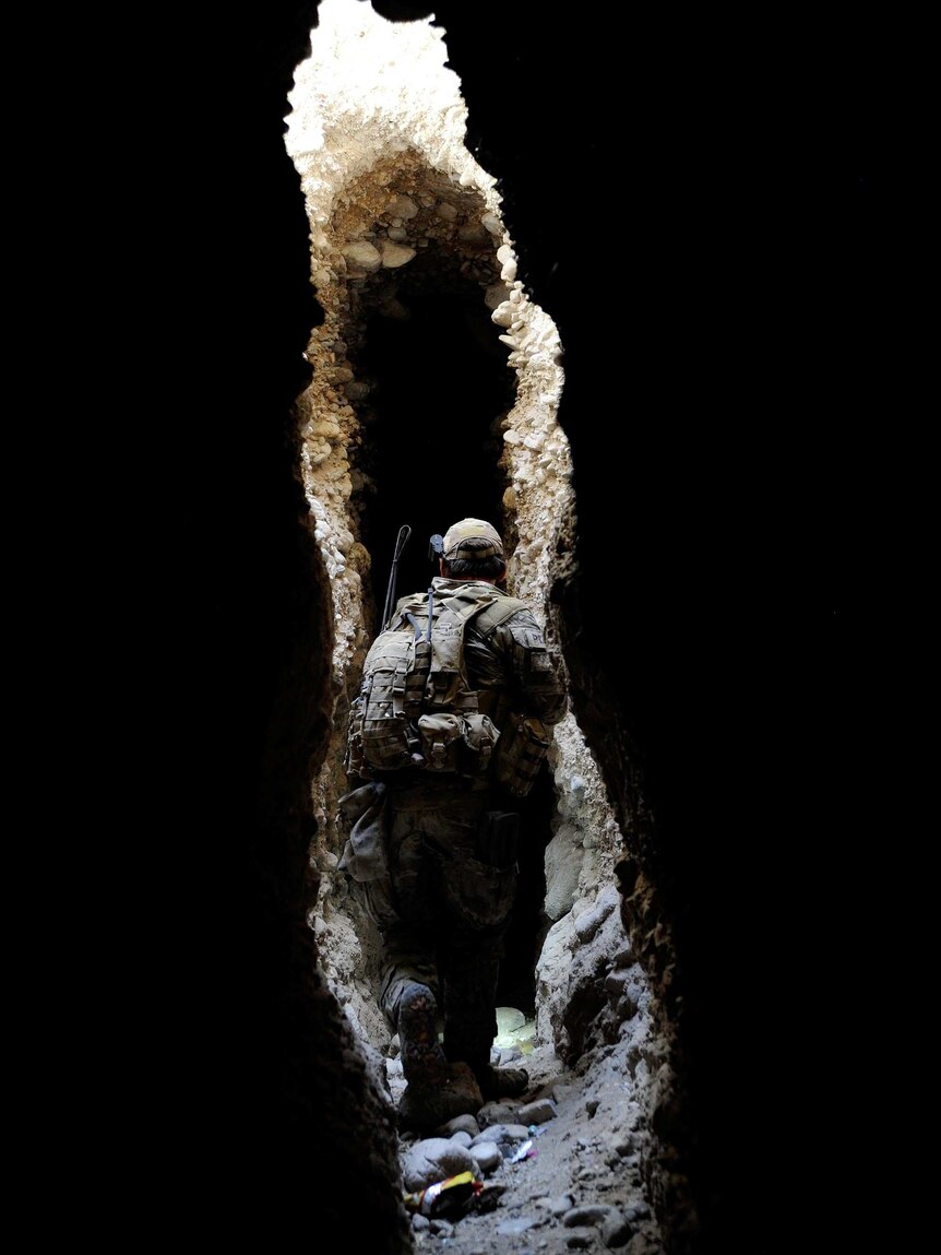 A Special Operations Task Group soldier searches a cave system for drugs.