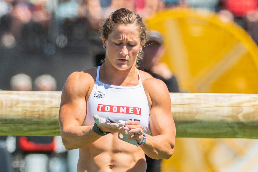 A woman rubs her hands together while walking between obstacles.