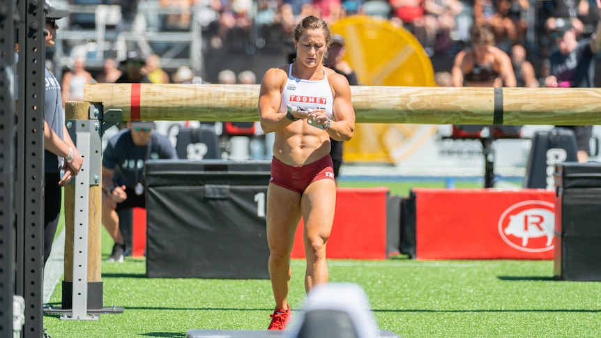 A woman rubs her hands together while walking between obstacles.