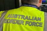 Unidentified Australian Border Force worker seen from behind, at airport security.