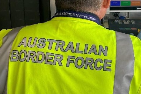 Unidentified Australian Border Force worker seen from behind, at airport security.