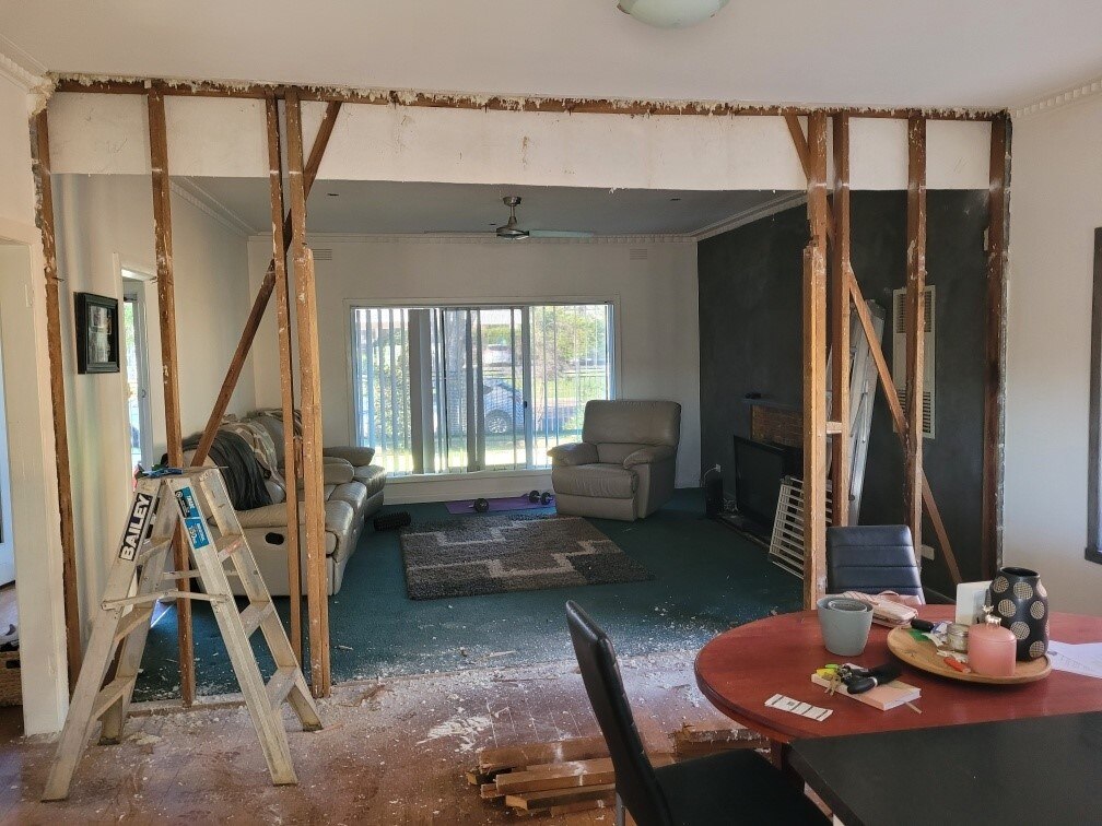 Beams where the wall between the kitchen and lounge room used to be, dusty particles covering the ground