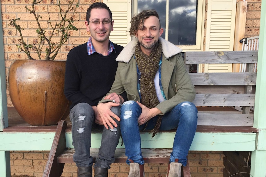 Neil Car and Terry Cass sit on the front steps of their house